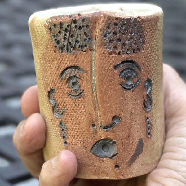 stoneware tumbler with carved facial features