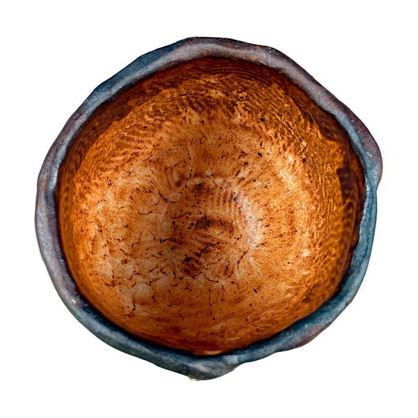 An overhead view of a rustic ceramic bowl with a textured, earthy brown interior and a dark, slightly glazed exterior, isolated on a white background.